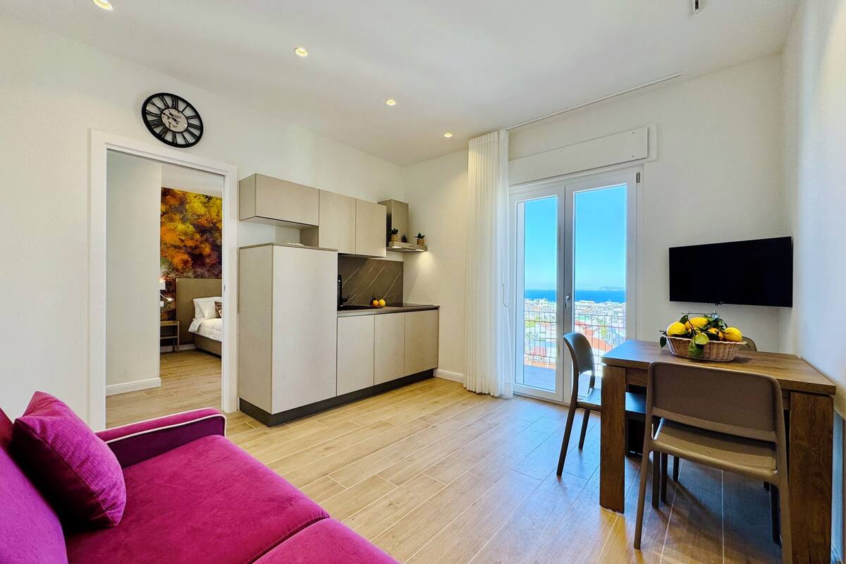 Un apartamento moderno con cocina, comedor y sala de estar con un sofá rosa.