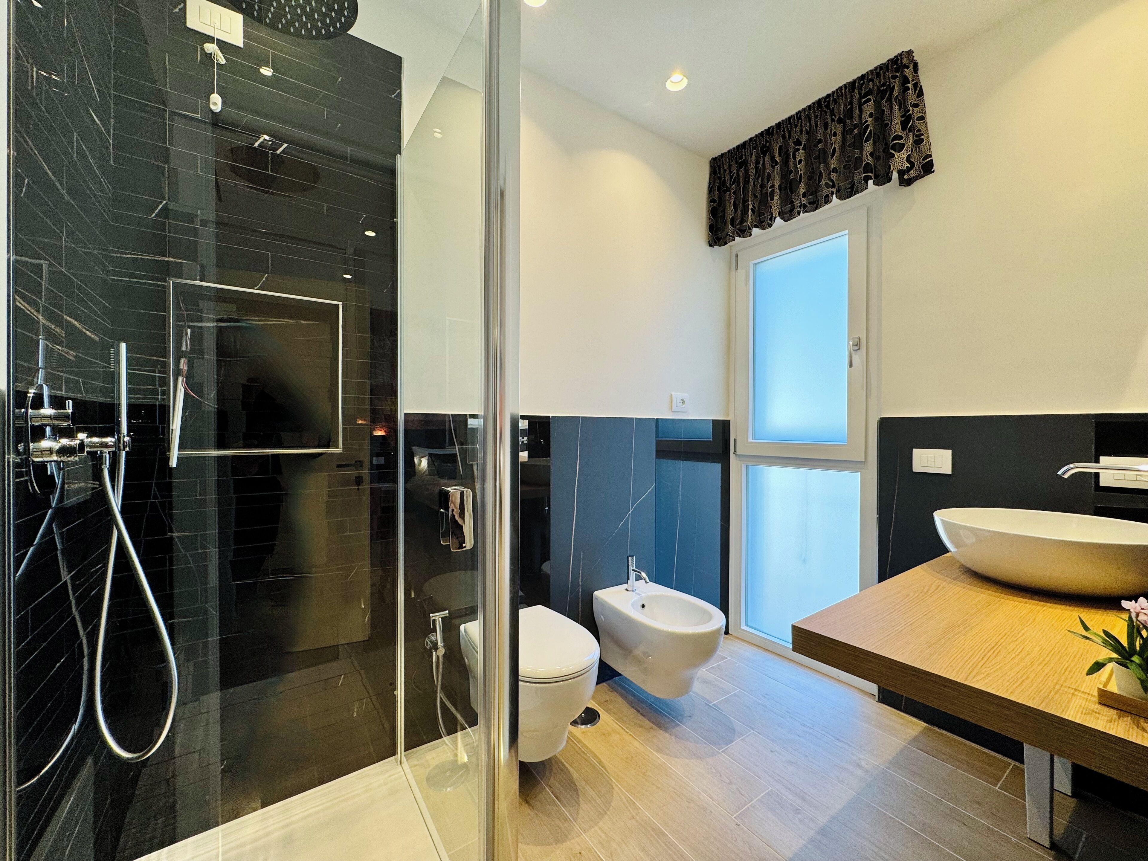 A modern bathroom with a glass-enclosed shower, a toilet, and a sink with a large basin.