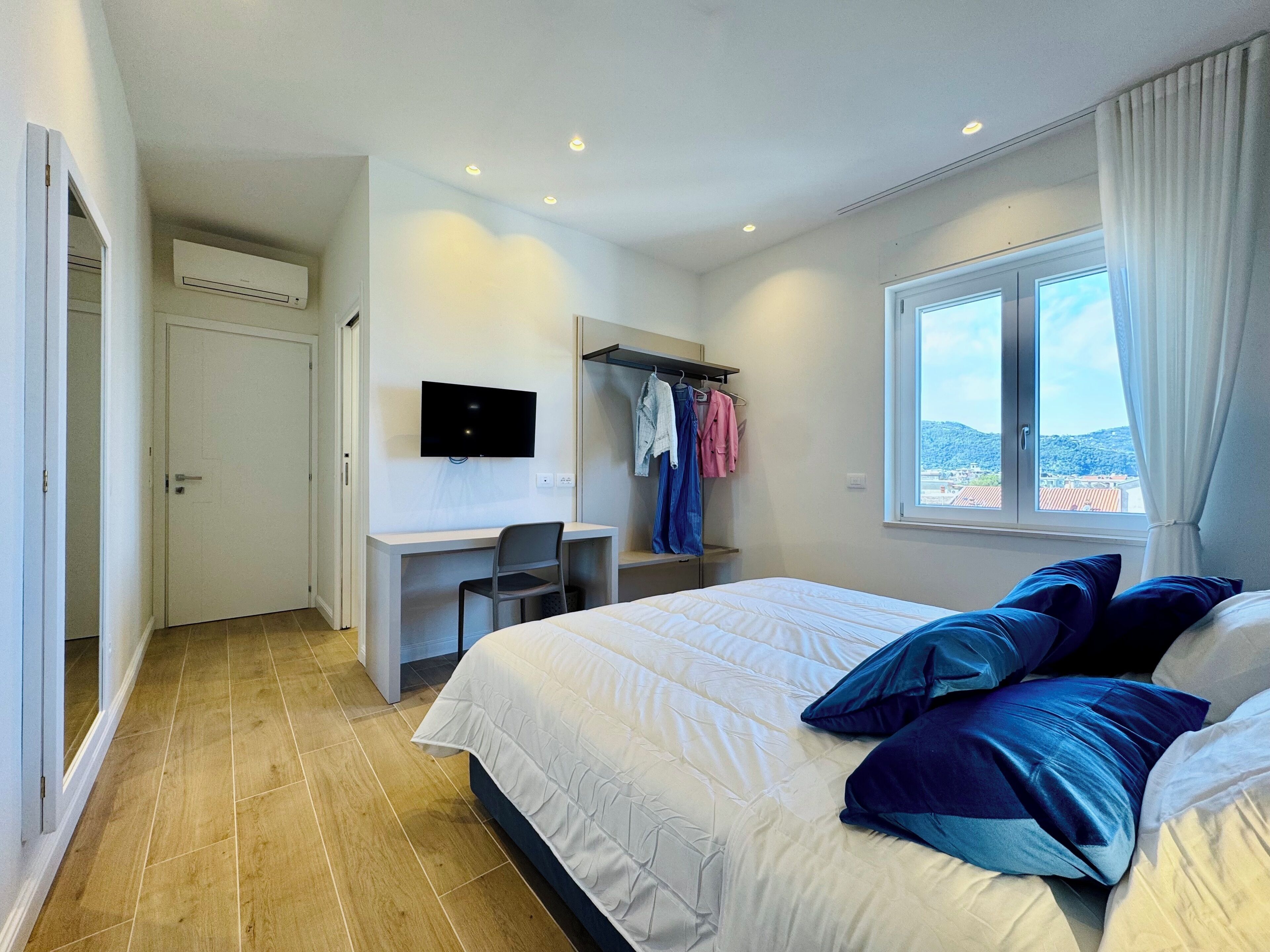 Ein Schlafzimmer mit Bett, Schreibtisch, Stuhl, Fernseher und einem Fenster mit Blick.