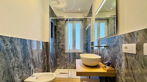 Une salle de bain moderne dotée d’une baignoire sur pieds, d’un grand lavabo avec un receveur et d’un espace douche avec une porte en verre.