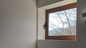 A bedroom with two single beds, a window with a view of bare trees, and a wooden headboard. - Brioso Cutlery House (Outeiro)