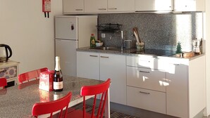 A modern kitchen with white cabinets, a granite countertop, and a red chair. - Brioso Cutlery House (Outeiro)
