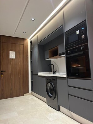 A modern kitchen with built-in appliances, a washing machine, and a wooden door. - UNO CAPITAL (Casablanca)