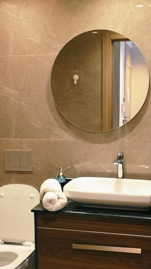 A bathroom with a round mirror, a sink, a toilet, and a towel. - UNO CAPITAL (Casablanca)