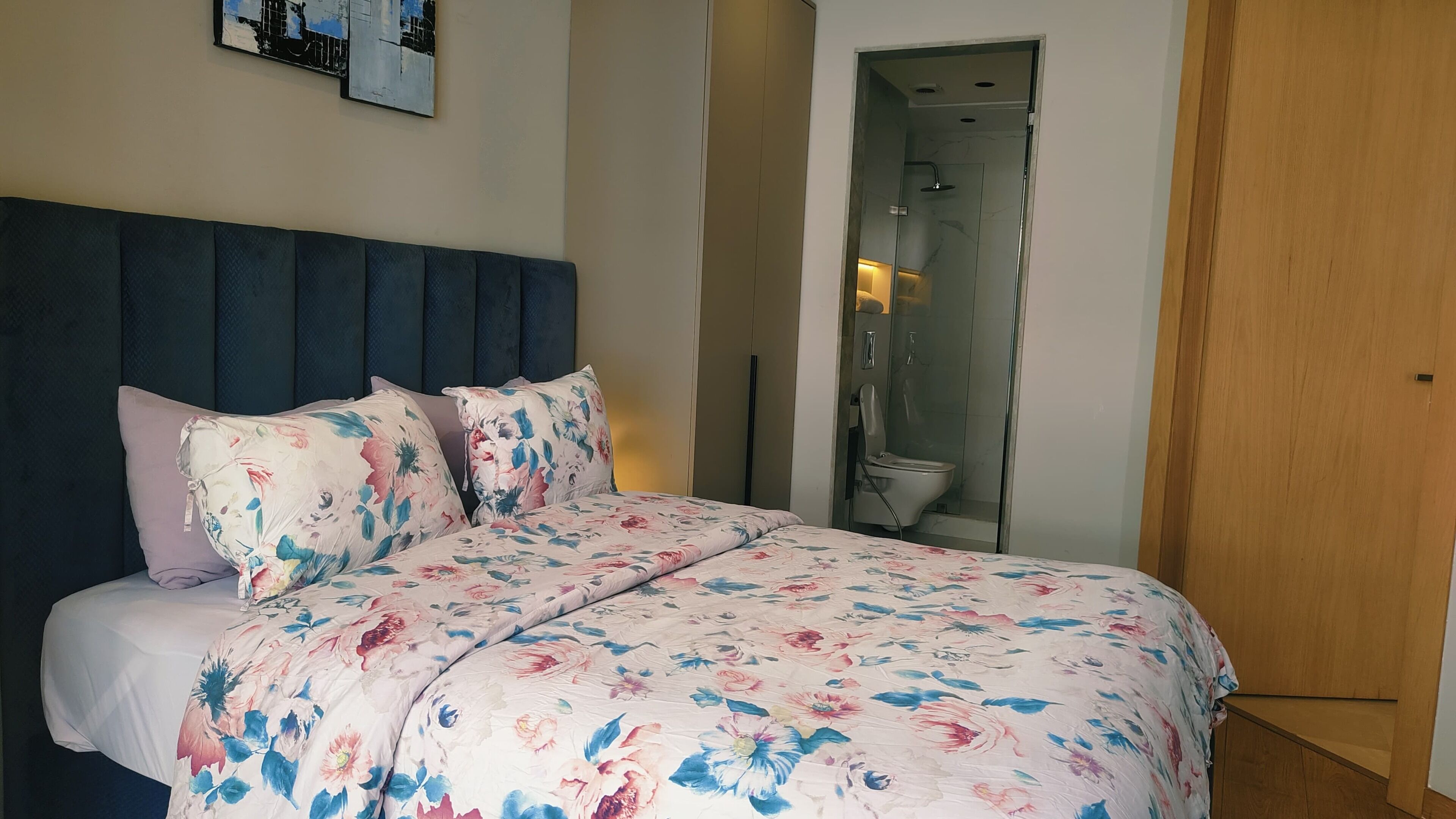 Un dormitorio con cama, cabecera, ducha y puerta de madera.