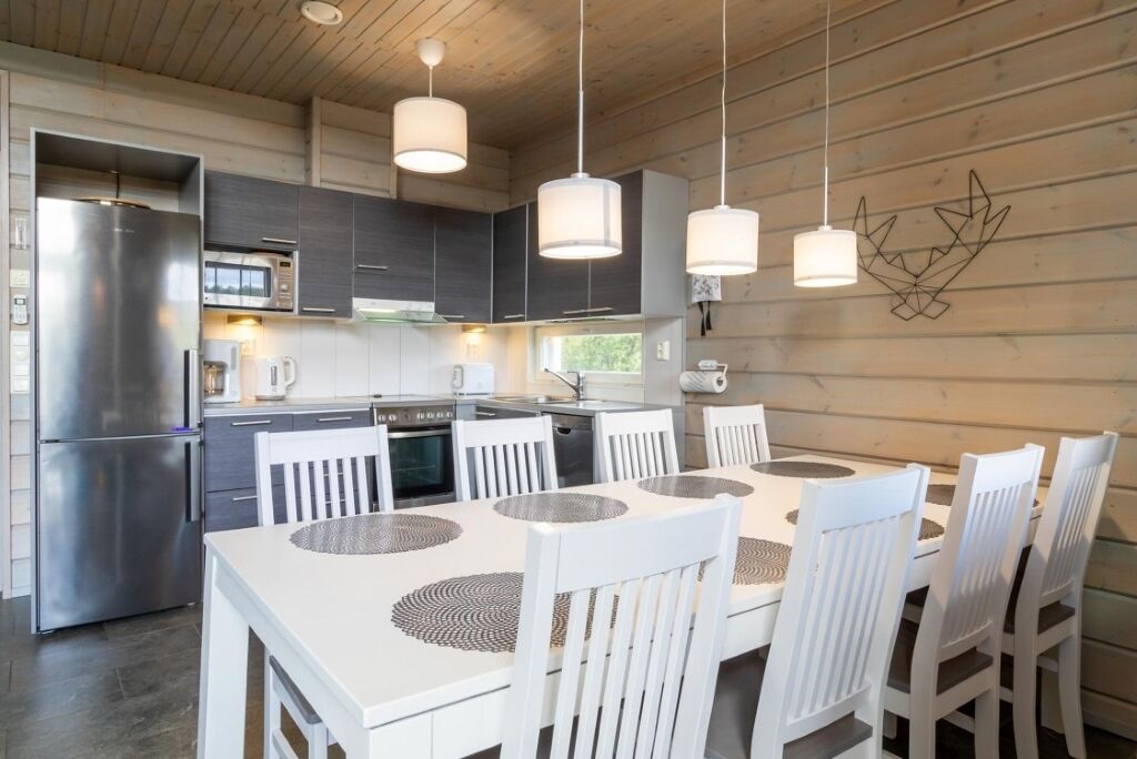 A modern kitchen with white cabinetry, stainless steel appliances, and a dining area with white chairs and a white table.