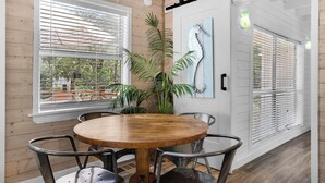 A room with a wooden table and chairs, large windows with blinds, a potted plant, and a wall-mounted light fixture. - 2BR Home, Private Heated Pool, 4 Bikes, Beach Access (Santa Rosa Beach)