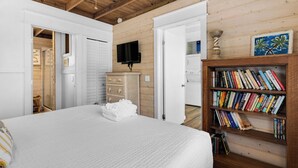 A bedroom with a bed, a bookshelf, a television, and a wooden wardrobe. - 2BR Home, Private Heated Pool, 4 Bikes, Beach Access (Santa Rosa Beach)