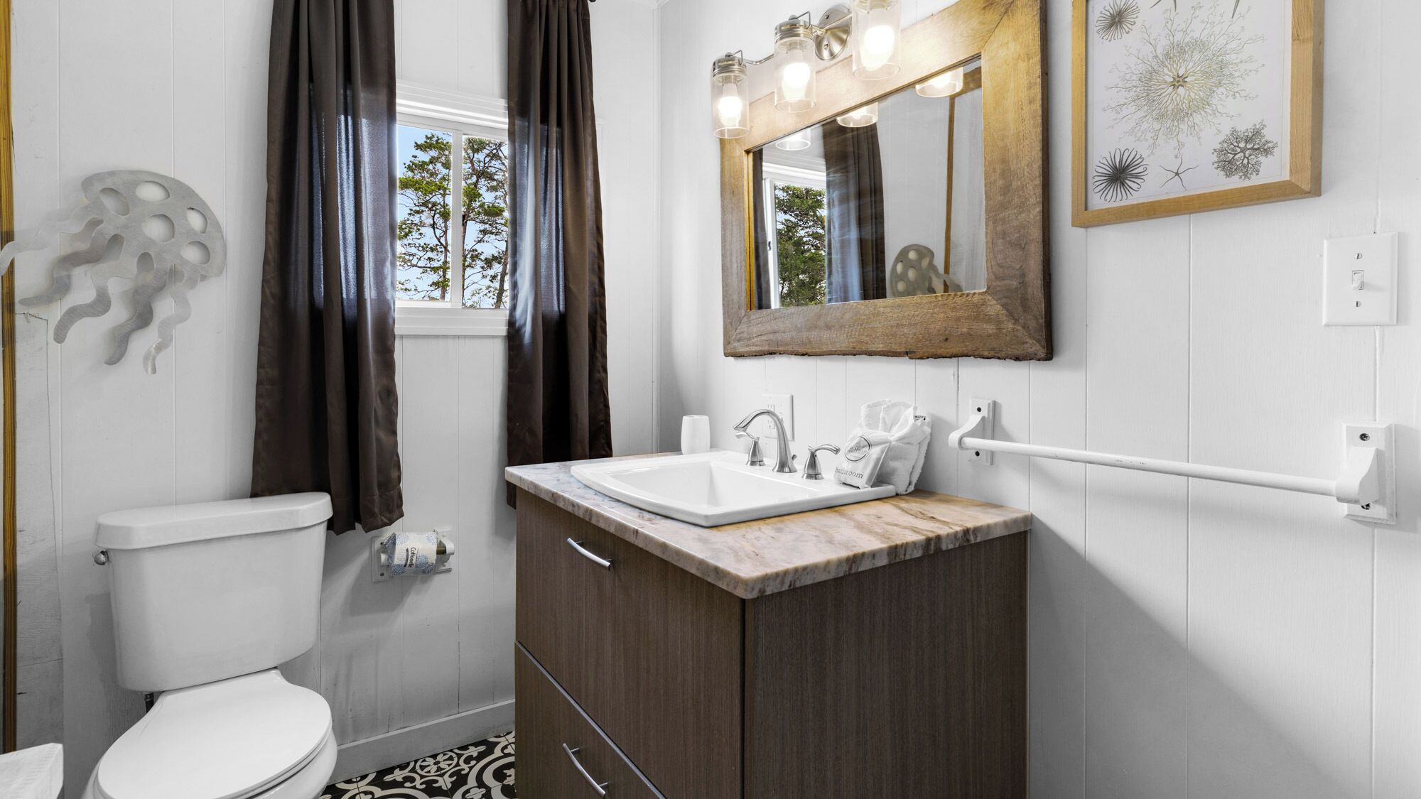 Un baño moderno con inodoro blanco, lavamanos de mármol y tocador de madera.
