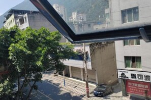 Vista de una calle con edificios, un árbol y un coche estacionado.