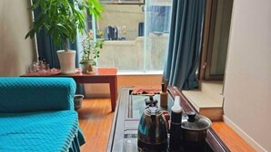 A room with a bed, a table with a kettle and a pot, a plant, and a view through a window. - Asbestos Jiayi Hotel (Shimian)
