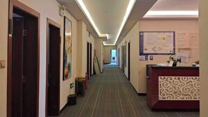 A hotel hallway with doors on the left, a reception desk on the right, and a long corridor. - Asbestos Jiayi Hotel (Shimian)
