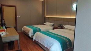A hotel room with two beds, a desk, a chair, and a nightstand with a lamp. - Asbestos Jiayi Hotel (Shimian)