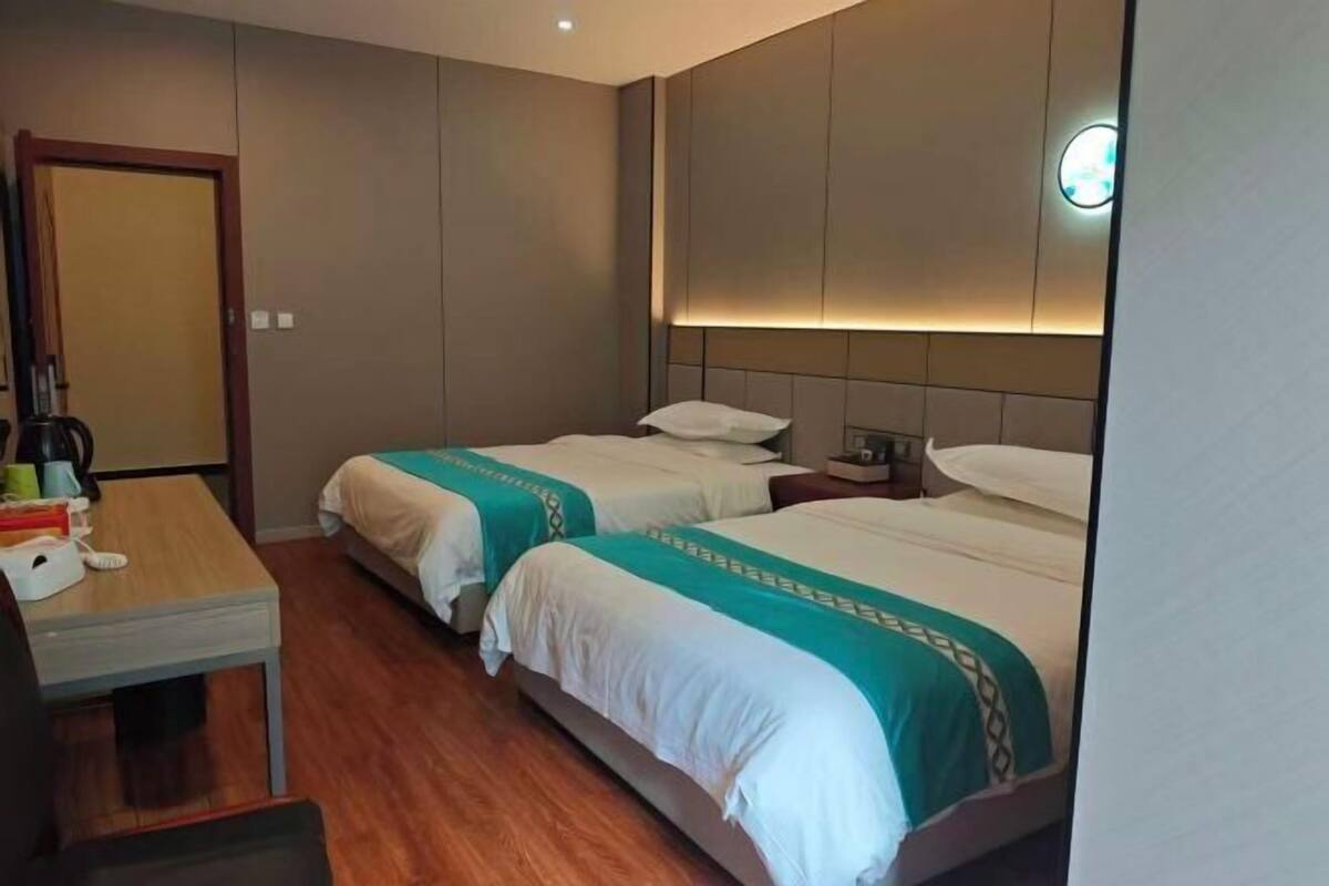 Een hotelkamer met twee bedden, een bureau, een stoel en een nachtkastje met een lamp.