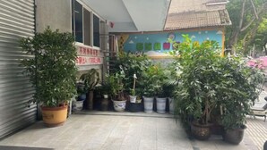 A courtyard with potted plants, a closed shop, and a colorful mural on the wall. - Asbestos Jiayi Hotel (Shimian)