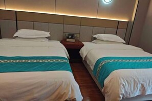Een hotelkamer met twee bedden, een nachtkastje en een wandlamp.