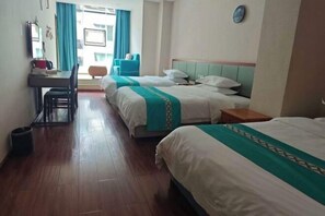Een hotelkamer met drie bedden, een bureau en een stoel.