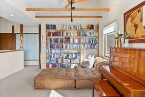 A room with a large bookshelf, a sofa, a wooden desk, and a globe on the wall.