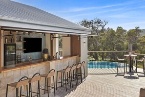 A bar area with stone counter and bar stools, overlooking a swimming pool. - Janacwal - Where Escape Meets Adventure (Bells Beach)