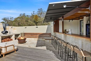 An outdoor patio with stone flooring, a fire pit, bar stools, and a seating area with cushions. - Janacwal - Where Escape Meets Adventure (Bells Beach)