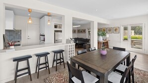 Uma cozinha moderna com bancada, mesa de jantar com cadeiras e área de estar com sofá e mesinha de centro.