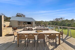 An outdoor deck with a dining table and chairs, a fire pit, and a covered seating area.