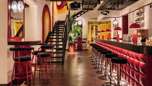 A bar area with red bar stools, a staircase, and a plant.