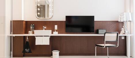 A modern bathroom with a vanity, mirror, and a television.