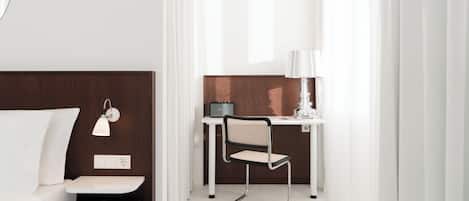 A modern hotel room with a bed, a desk with a chair, a lamp, and a Marshall amplifier.