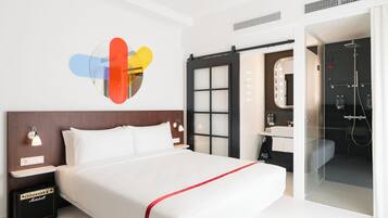 Et moderne hotelværelse med en stor seng, et sminkebord med spejl og et brusebadekar.