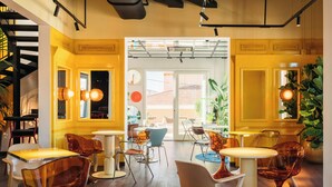 A modern interior with yellow walls, wooden floors, and a mix of orange and white furniture.