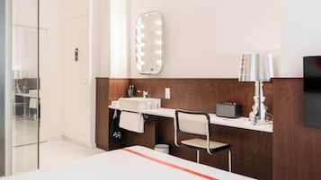 Un bagno moderno con specchiera, uno specchio e una sedia.