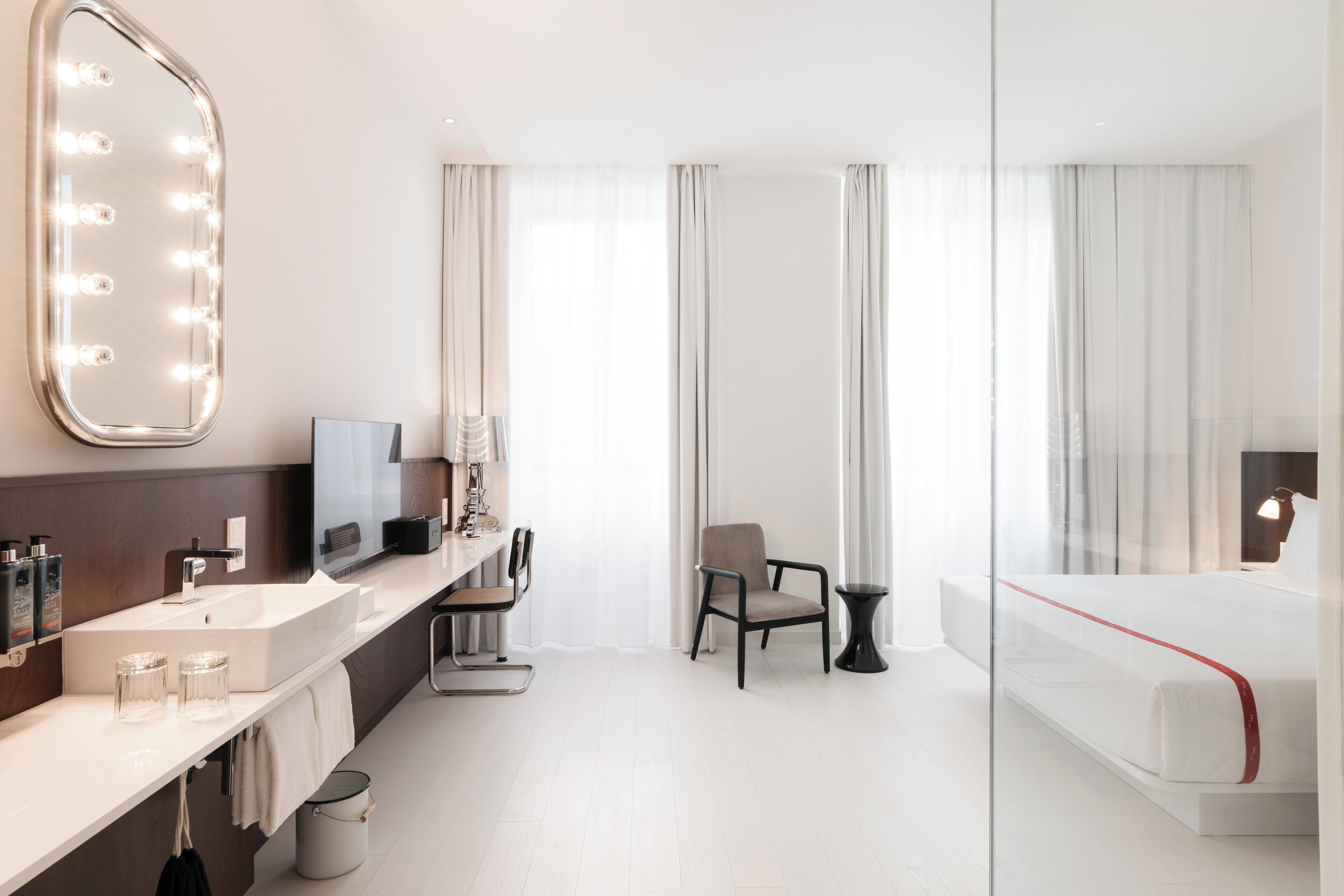 A modern hotel room with a large mirror, vanity, and a bed.
