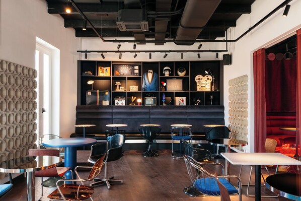 A modern interior with a seating area, a display of vintage items, and a patterned wall.