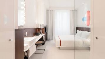 Ein modernes Hotelzimmer mit einem großen Bett, einem Schminktisch mit Spiegel und einem Schreibtisch mit Stuhl.