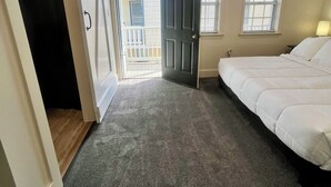 Un dormitorio con cama, armario, puerta que da a un balcón y ventana.