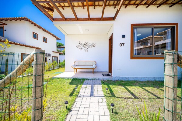 Una casa moderna con entrada empedrada, una banca en el exterior y el número '07' en la pared.