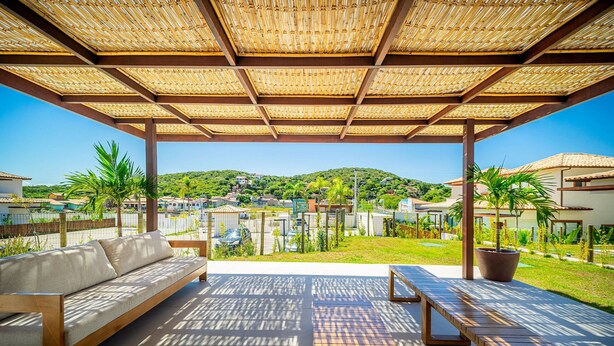 An outdoor patio with a bamboo roof, a sofa, and a table. - Bz95 Cond. Viva Búzios Casa 4 quartos (Búzios)