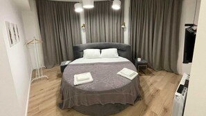 Et moderne soveværelse med en stor seng, et natbord, en hængende lampe og et garderobeskab.