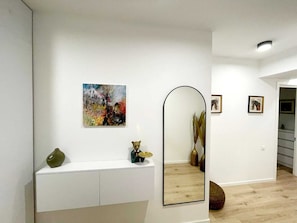 Un intérieur moderne avec une console blanche, un grand miroir et un tableau abstrait.