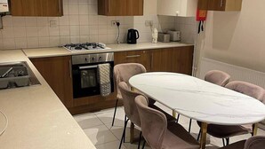 Eine moderne Küche mit Holzschränken, einem Gasherd, einem Backofen, einem Spülbecken und einem Esstisch mit Stühlen.