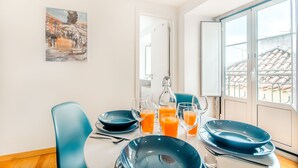 A dining area with a table set for four, including plates, glasses, and a bottle of orange juice. - Charming Flat in Alfama (Lisbon)