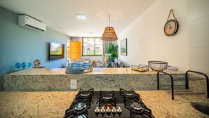 A kitchen with granite countertops, a gas stove, and a hanging rattan light fixture.