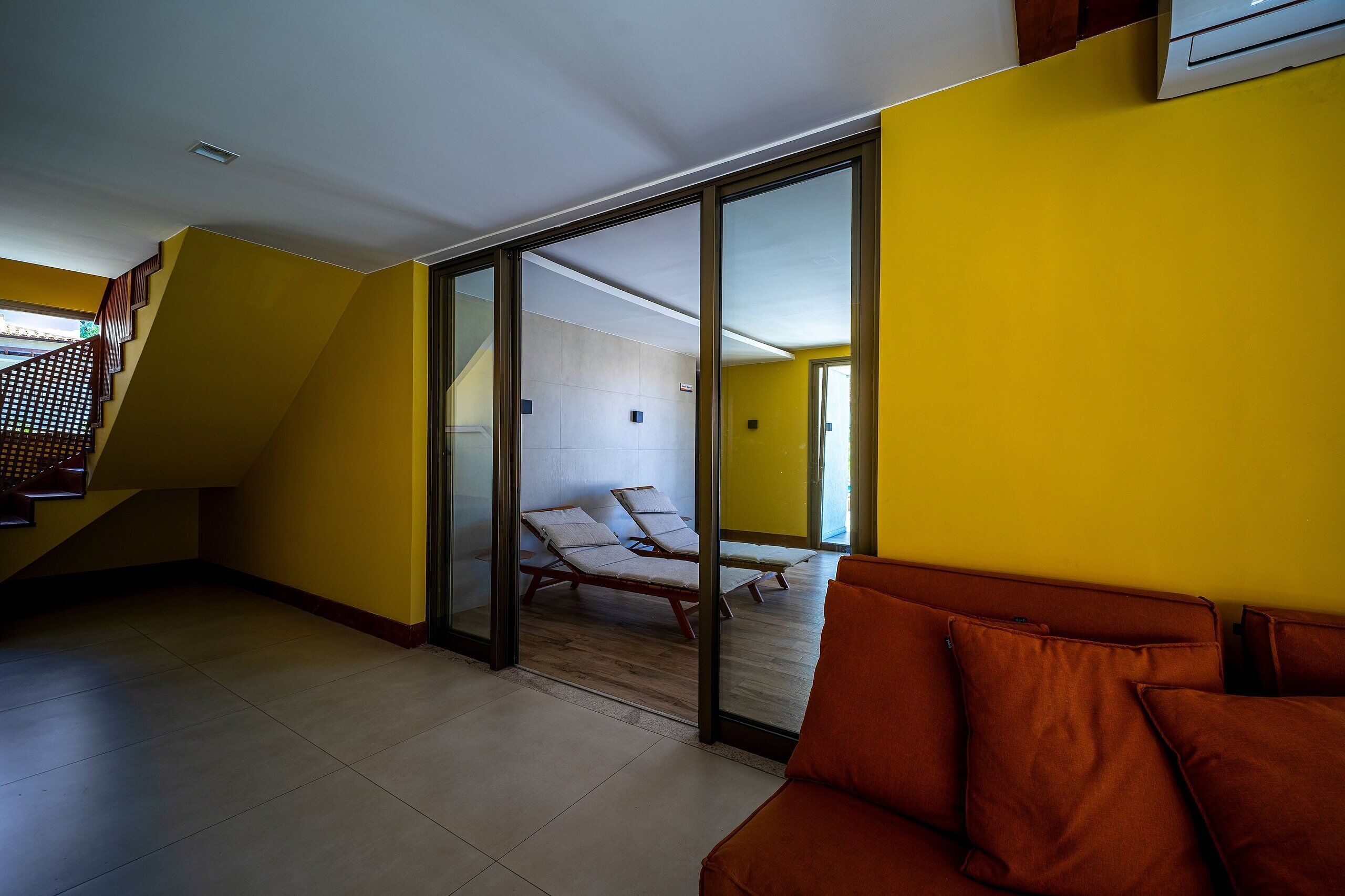 A modern interior with a yellow wall, a staircase, and a seating area with cushions.