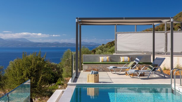 Zona de piscina con un pérgola, sillas de descanso y vista al mar.