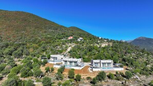 Una villa moderna con piscina, rodeada por un paisaje montañoso.