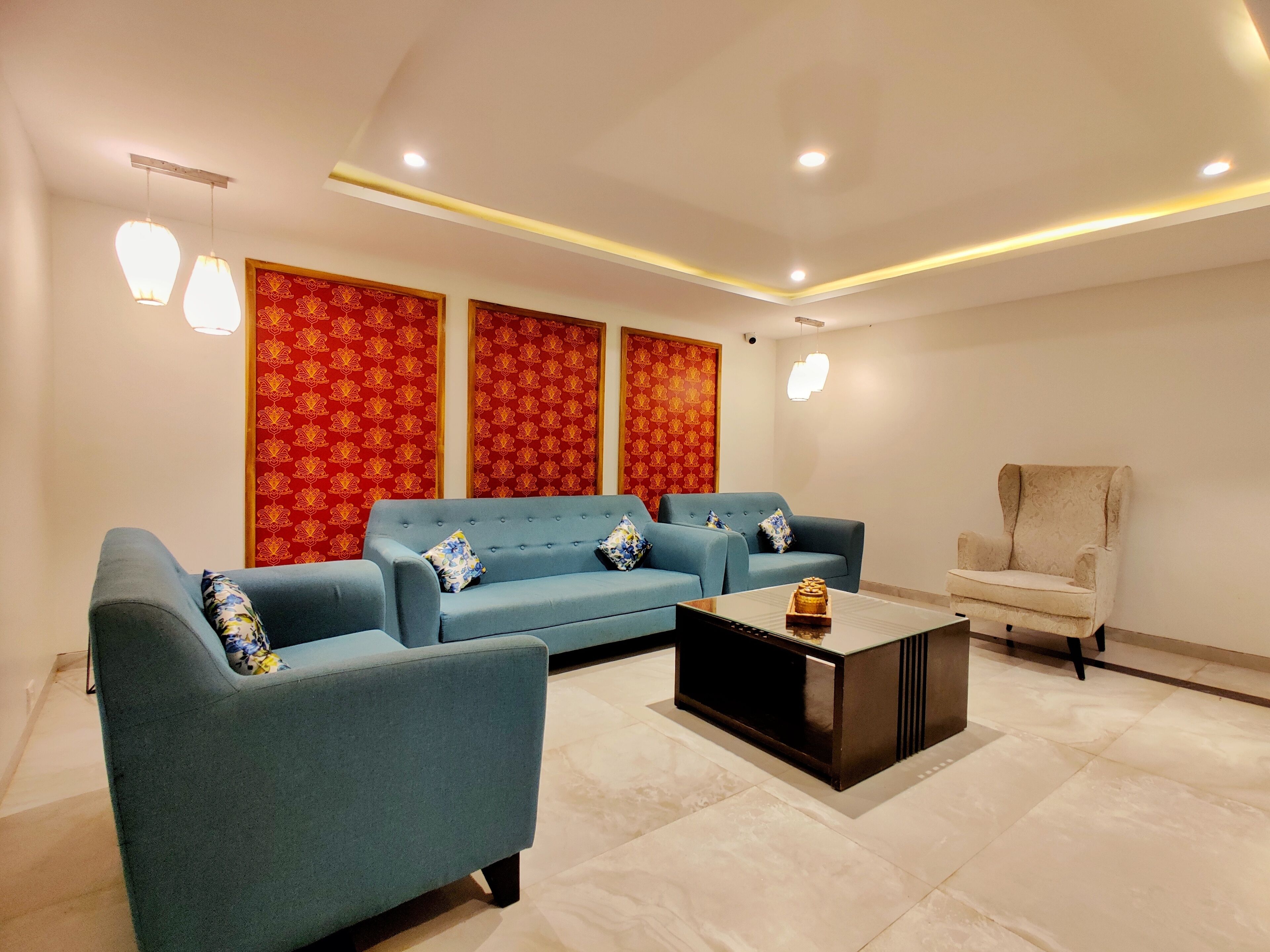 A modern living room with a blue sofa set, a coffee table, and a beige armchair.