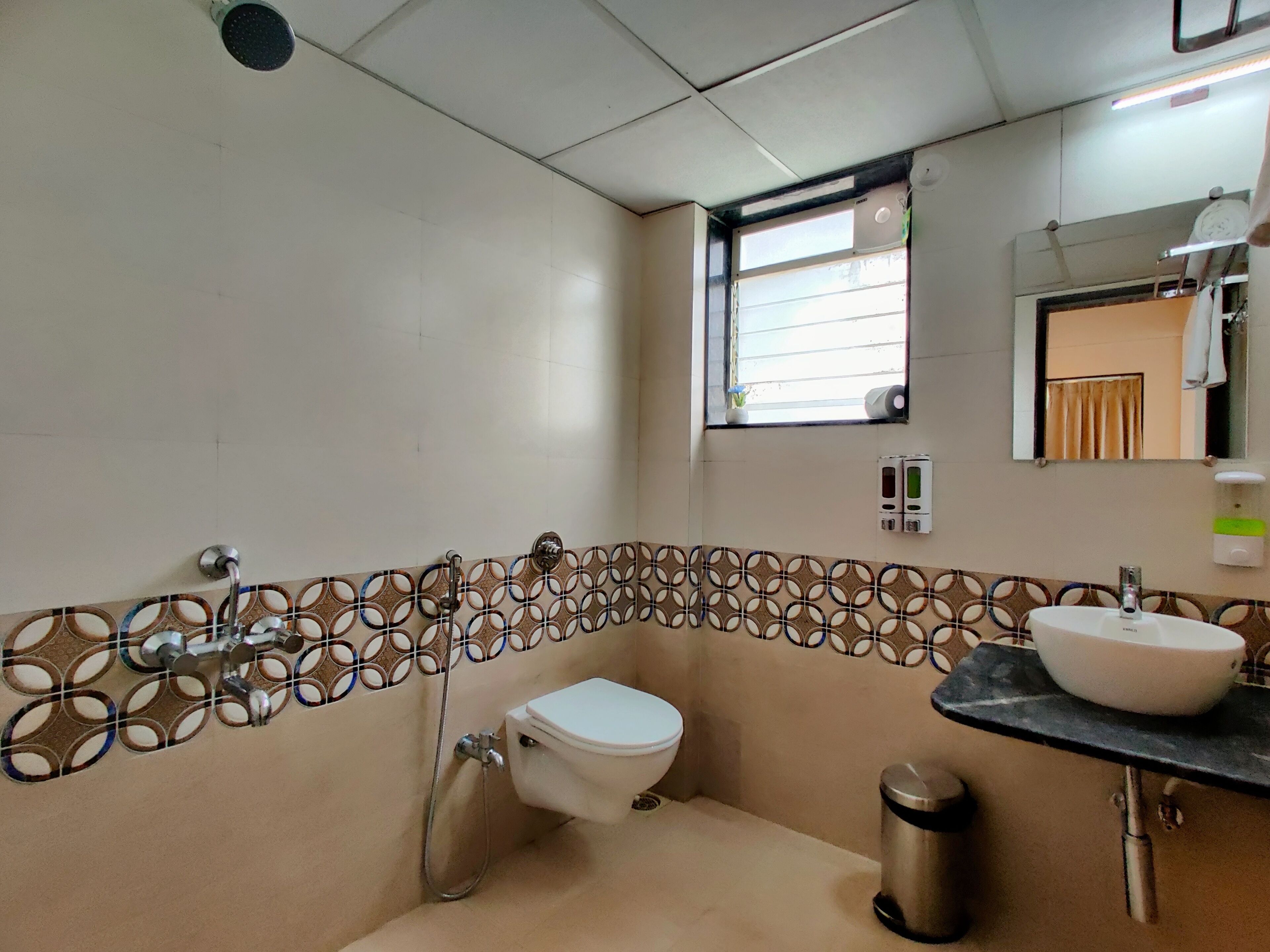 A bathroom with a toilet, a sink, a mirror, and a window.