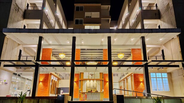 A multi-story hotel with a central lobby, multiple balconies, and a reception area. - Pushpam sanskruti Resort (Karjat)