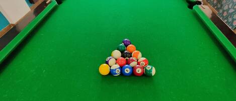 A pool table with a triangular arrangement of billiard balls and a cue ball in the center.